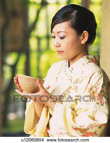 Picture - Woman in kimono holding a tea cup at tea ceremony, side view, Japan, differential focus. Fotosearch