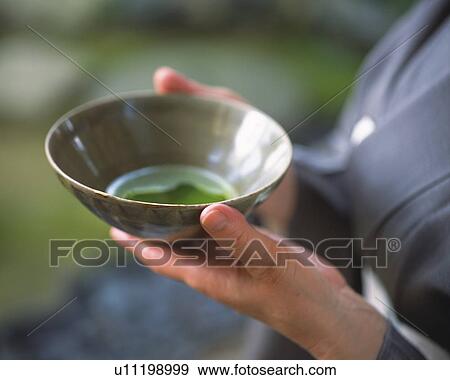 Stock Photo - Woman in kimono holding a tea cup at tea ceremony, side view, close up, Japan, differential focus. Fotosearch