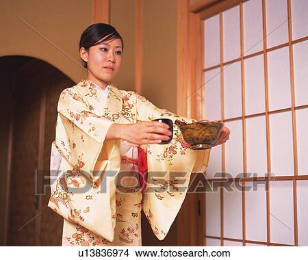 Woman in kimono standing and holding Japanese cups in a tea room, low angle view, Japan View Large Photo Image Picture - Woman in kimono standing and holding Japanese cups in a tea room, low angle view, Japan. Fotosearch
