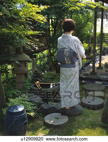 Stock Image - Woman in kimono standing in Japanese garden, rear view, Japan. Fotosearch