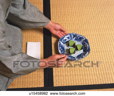 Stock Image - Woman in kimono taking shi at tea ceremony, high angle view, Japan. Fotosearch