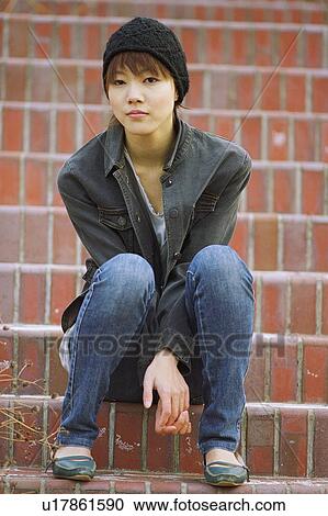 Stock Image - Portrait of a young woman sitting on stairs. Fotosearch