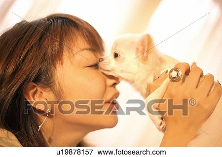 Stock Photo - Side profile of a young woman holding a puppy . Fotosearch