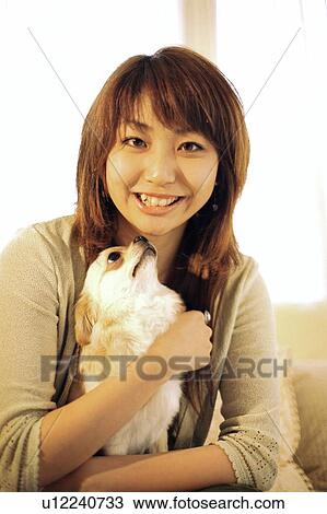 Stock Image - Young woman holding a puppy . Fotosearch