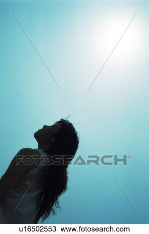 Stock Image - Young woman looking up the sky. Fotosearch
