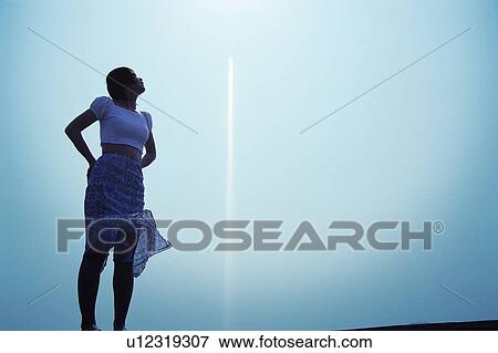 Stock Photo - Young woman looking up the sky. Fotosearch