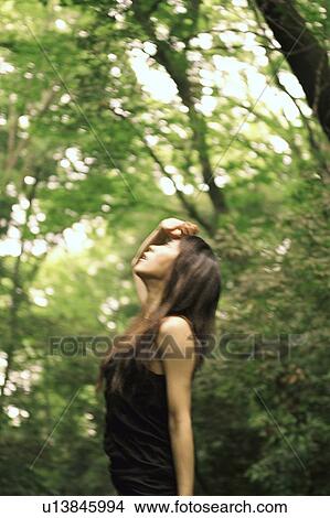 Picture - Young woman looking up with her hand on her forehead . Fotosearch