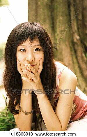 Stock Image - Young woman smiling with hands on chin . Fotosearch