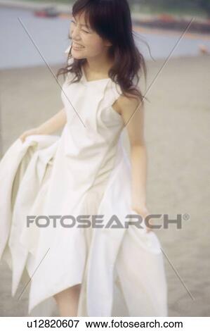 Young woman standing on the beach, wearing white one-piece dress View Large Photo Image Stock Photo - Young woman standing on the beach, wearing white one-piece dress . Fotosearch