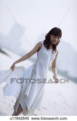 Stock Image - Young woman walking the beach. Fotosearch