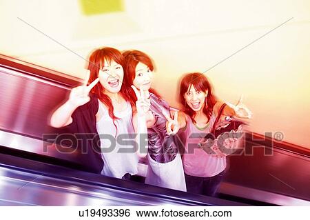 Stock Photograph - Three Young Adult Women at the escalator. Fotosearch