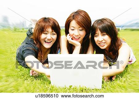 Stock Image - Three Young Adult Women using a Computer. Fotosearch