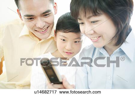 Stock Photo - Family checking a portable telephone. Fotosearch