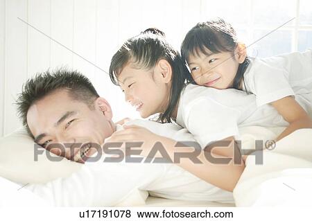 Stock Photo - Family relaxing in bed room. Fotosearch
