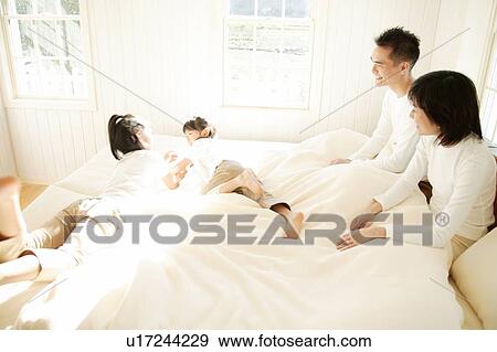 Stock Photo - Family relaxing in bed room. Fotosearch