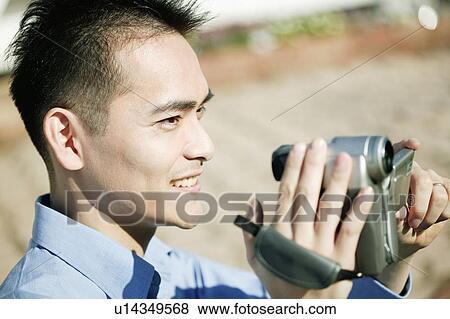 Stock Photo - Man taking a video camera. Fotosearch