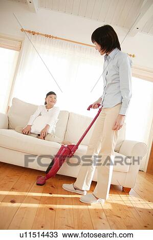 Stock Image - Mother cleaning up living room. Fotosearch