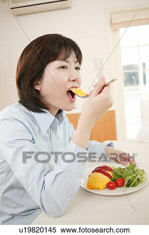 Stock Photography - Woman eating a meal. Fotosearch