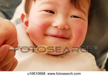 Stock Photo - A Baby Girl eating baby food. Fotosearch