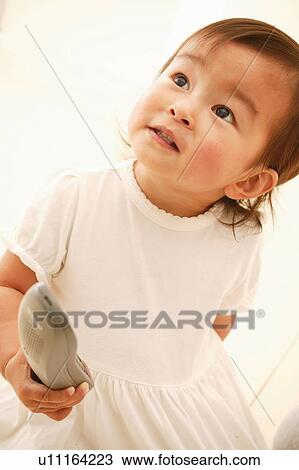 Stock Image - A Baby Girl holding a phone. Fotosearch