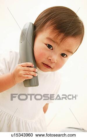 A Baby Girl listening by the phone View Large Photo Image Stock Image - A Baby Girl listening by the phone. Fotosearch