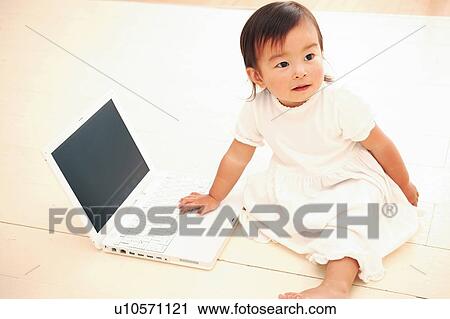 Stock Image - A Baby Girl playing with a computer. Fotosearch