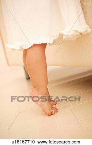 Stock Image - A Baby Girl standing on tiptoe. Fotosearch