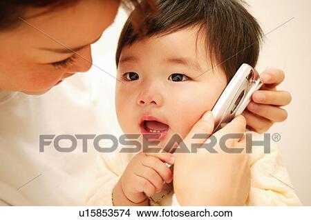 Picture - A Baby Playing with a mobile phone. Fotosearch