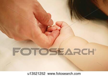 Stock Image - Father holding his baby's hand. Fotosearch