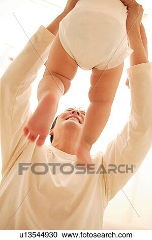 Stock Image - Father holding up his baby. Fotosearch