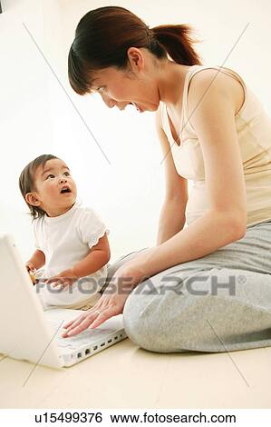 Stock Photograph - Mother and her daughter playing with a computer together. Fotosearch