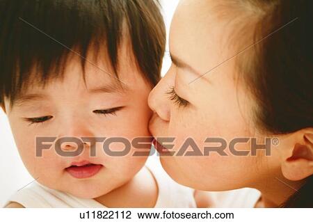 Stock Image - Mother kissing her baby. Fotosearch