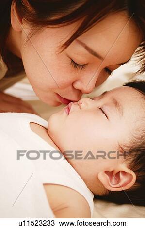 Stock Image - Young Mother kisses her Baby. Fotosearch