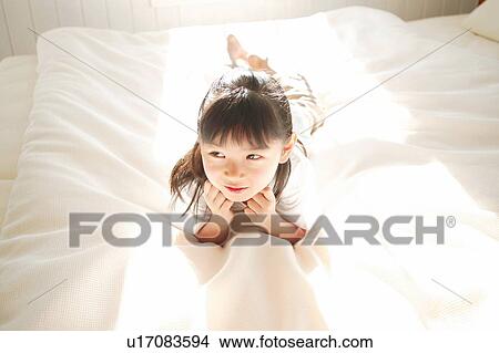 Picture - A Young Girl lying down on the bed. Fotosearch