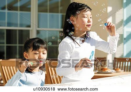 Stock Photo - Young Girls blowing soap bubbles. Fotosearch