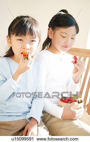 Stock Image - Young Girls eating strawberrys. Fotosearch