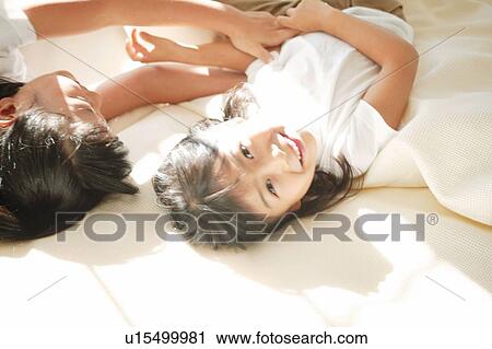Young Girls lying down on the bed View Large Photo Image Stock Image - Young Girls lying down on the bed. Fotosearch