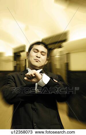 Stock Image - Businessman Looking Wrist Watch. Fotosearch