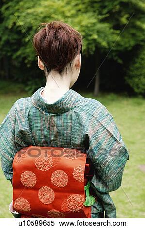 Stock Photography - Woman putting on a kimono, back style. Fotosearch