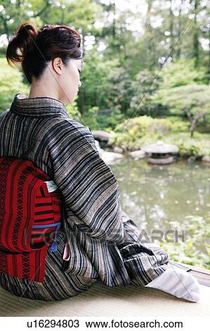 Stock Image - Woman putting on a kimono. Fotosearch
