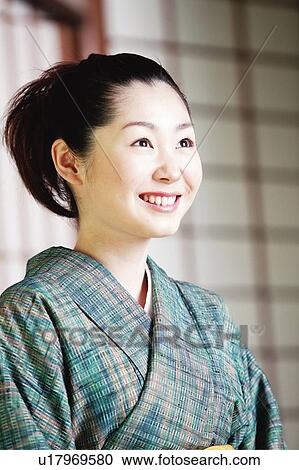 Stock Image - Woman putting on a kimono. Fotosearch