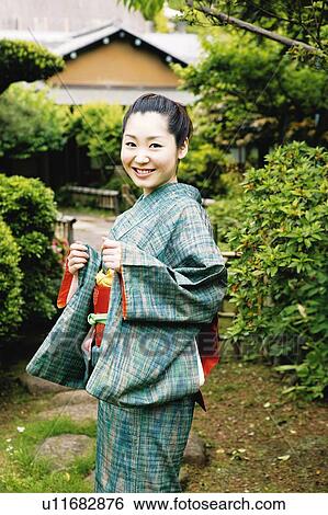 Stock Photograph - Woman putting on a kimono. Fotosearch