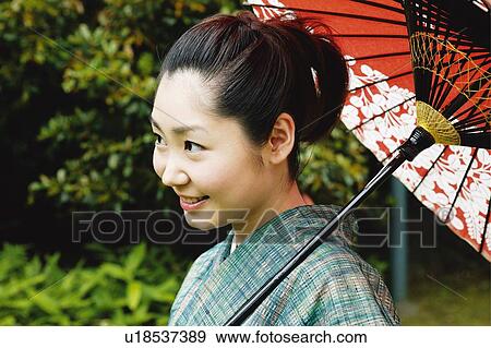Stock Photo - Woman putting up a Japanese umbrella. Fotosearch