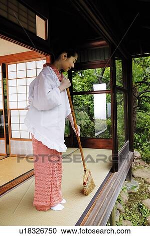 Stock Image - Woman sweeping a house with a bloom. Fotosearch