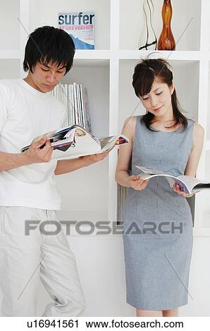 Stock Image - Couple reading magazines in the room. Fotosearch