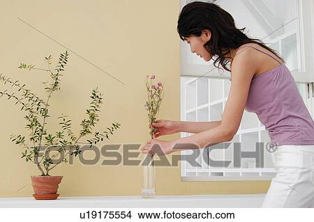 Picture - Woman arranging flowers in a vase. Fotosearch
