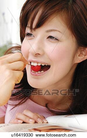 Stock Image - Woman eating a cherry, Close-up. Fotosearch