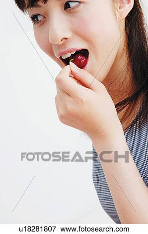 Stock Photo - Woman eating a cherry, Close-up. Fotosearch