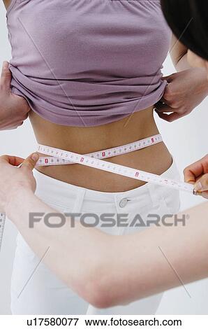 Stock Photo - Woman measuring the friend's waist size. Fotosearch