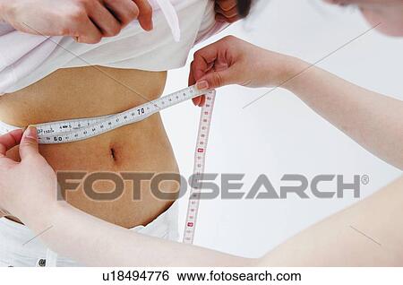 Stock Photograph - Woman measuring the friend's waist size. Fotosearch
